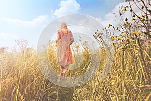 Dreamy woman walking in nature towards the sun