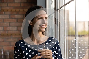 Dreamy young woman begin day from glass of pure water