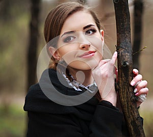Dreamy young woman in a black coat in autumn park