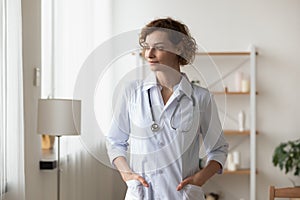 Dreamy young woman doctor wearing uniform looking to aside, visualizing