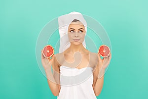 dreamy young woman in towel after shower with grapefruit on blue background