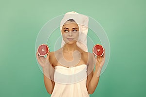 dreamy young woman in towel after shower with grapefruit on blue background