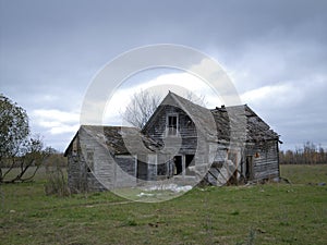 Dreary Abandoned Dilapidated Farm House with cloudy skies photo