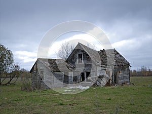 Dreary Abandoned Dilapidated Farm House with cloudy skies