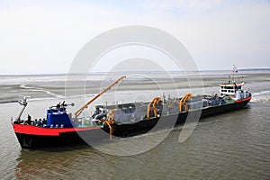 Dredger vessel in the Wadden Sea preventing the fairway from silting up