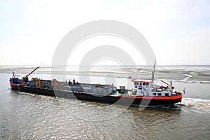 Dredger vessel in the Wadden Sea preventing the fairway from silting up