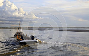 Dredger vessel in the Wadden Sea preventing the fairway from silting up