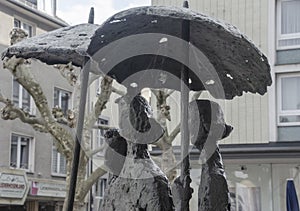 Drei Damen mit Regenschirm mit dem Titel Aachener Wetter, Bronzeskulptur