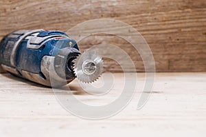 Dremel tool with installed small circular saw on a wooden boa photo