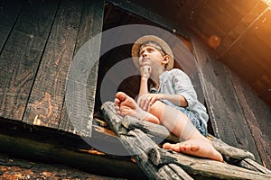 Dreming boy sits on the barn leader