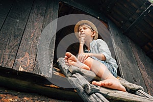 Dreming boy sits on the barn leader