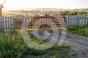 Drenched by dawn sun village fields and wooden gates.