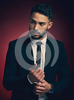 Dress for the job you want. Studio shot of a young man posing against a red background.