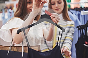 This dress is perfect Rear view of beautiful young woman trying on dress and looking at her reflection in the mirror