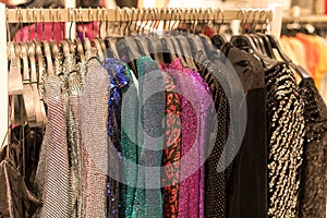 Dress-up, festive women `s clothes with glitter and payets on hangers in the store. Season of sale, black Friday, preparation for
