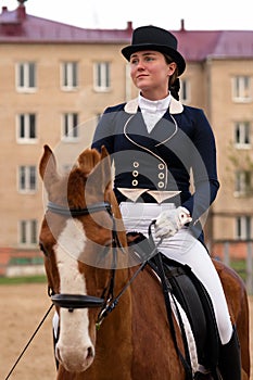 Dressage rider on chestnut horse with urban backdrop