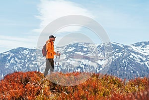 Oblečená jasně oranžová bunda batohem chodící po turistické cestě pomocí trekových holí v pohoří malá fatra, slovensko