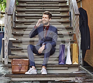 Dressed in his best for a day of retail therapy. Shot of a well dressed young man using his phone on a shopping spree.