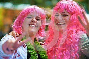 Dressed to the nines. Portrait of two young women dressed up in wigs at an outdoor festival.