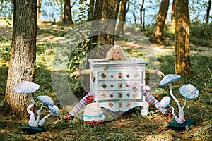 Dresser with doll Alice inside near Humpty Dumpty and mushrooms art object on outdoor art exhibition