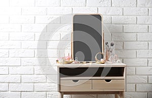 Dressing table with different makeup products and accessories in room interior