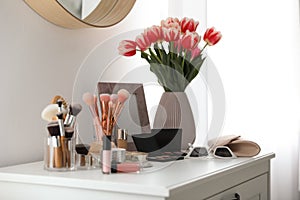 Dressing table with makeup products, accessories and tulips. Interior element