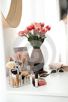 Dressing table with makeup products, accessories and tulips. Interior element