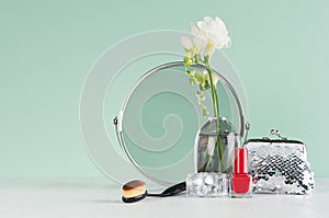 Dressing table in mint menthe with accessories for make up in silver with white flowers, round mirror, cosmetics bag, nail polish. photo