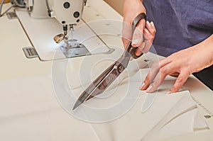 Dressmaker cuts white cloth with large knives