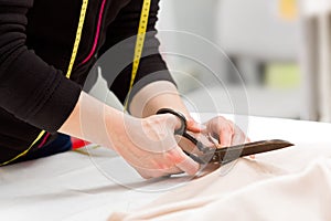 Dressmaker cutting fabric with scissors