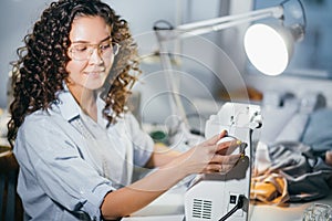 Dressmaker is fixing white sewing machine in workshop