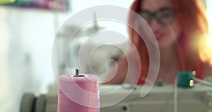 Dressmaker looks at the unwinding of the spool of thread while sewing