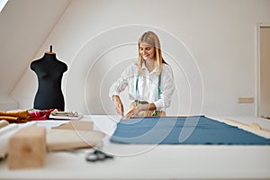 Dressmaker measures cloth at workplace in workshop