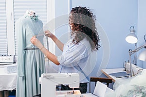 Dressmaker measuring breast of garmenr on dummy to make recesses