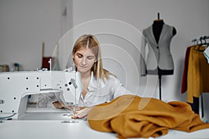 Dressmaker sews cloth on sewing machine, workshop