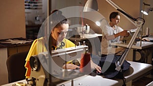 Dressmaker working on a sewing machine in tailor studio at table. Professional occupation of seamstress in fashion