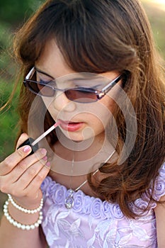 Dressy teen applies lipstick photo
