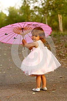 Dressy two-year-old girl carrying pink parasol photo
