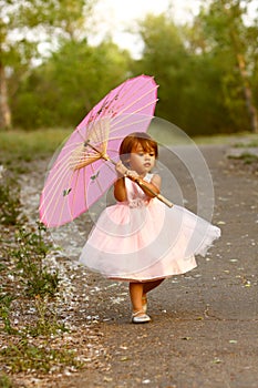 Dressy two-year-old girl carrying pink parasol photo