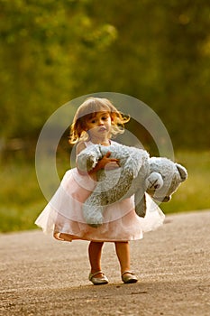 Dressy two-year-old girl carrying stuffed animal photo