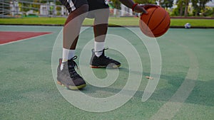 dribbling on basketball open ground, closeup of legs and hands of black sportsman, streetball