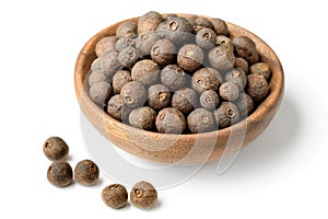 Dried allspice in the wooden plate, isolated on white background