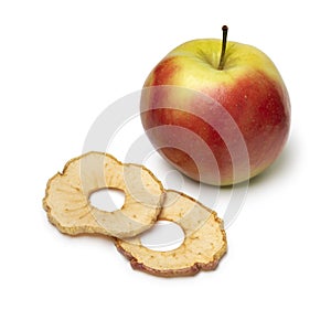 Dried apple chips and a fresh Elstar apple on white background