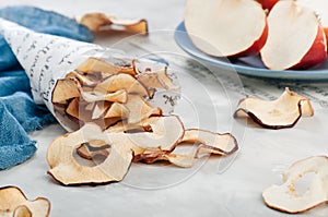 Dried apple slices in paper cornet on grey background