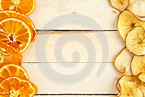Dried apples and oranges on wooden background. top view