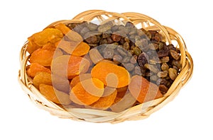 Dried apricots and raisins in wicker basket isolated on white