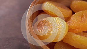 Dried apricots in rustic wooden bowl. Fresh dry fruits. Macro. Rotation.