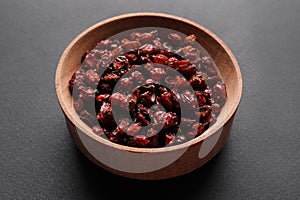Dried barberries in wooden bowl on grey background