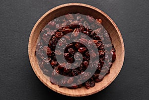 Dried barberries in wooden bowl on grey background, top view