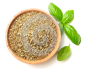 Dried basil leaves in the wooden plate, isolated on white, top view